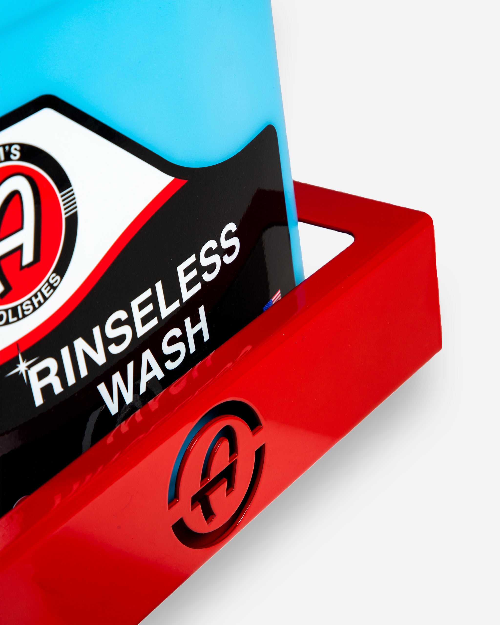 Close-up of a red Adam's 1 Gallon Holder with a blue rinseless wash bottle partially visible, featuring the Adam's logo on the shelf.