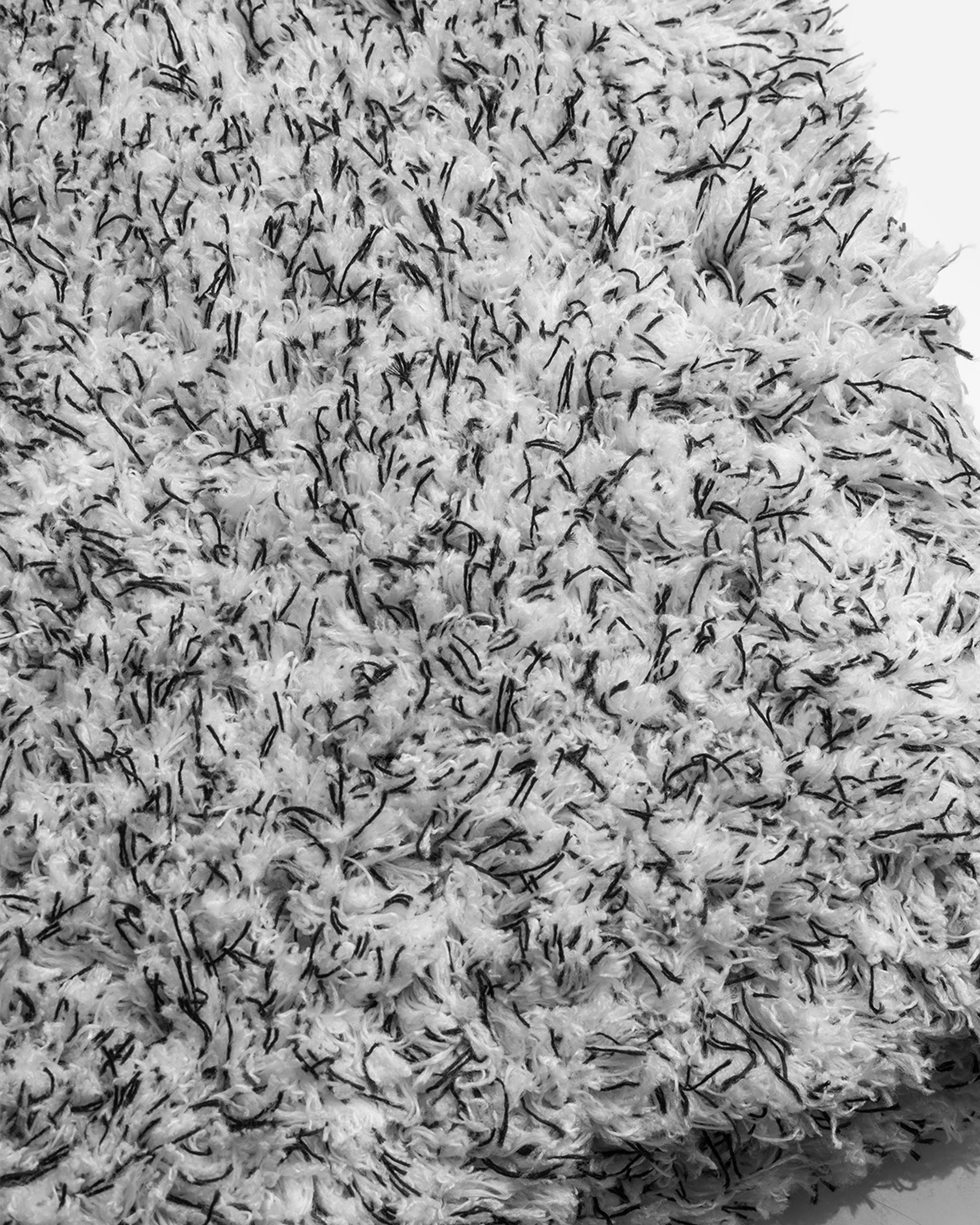 Close-up image of Adam's 10" Microfiber Wash Sponge showing its dense, plush fibers in black and white, illustrating the texture designed for efficient car washing.