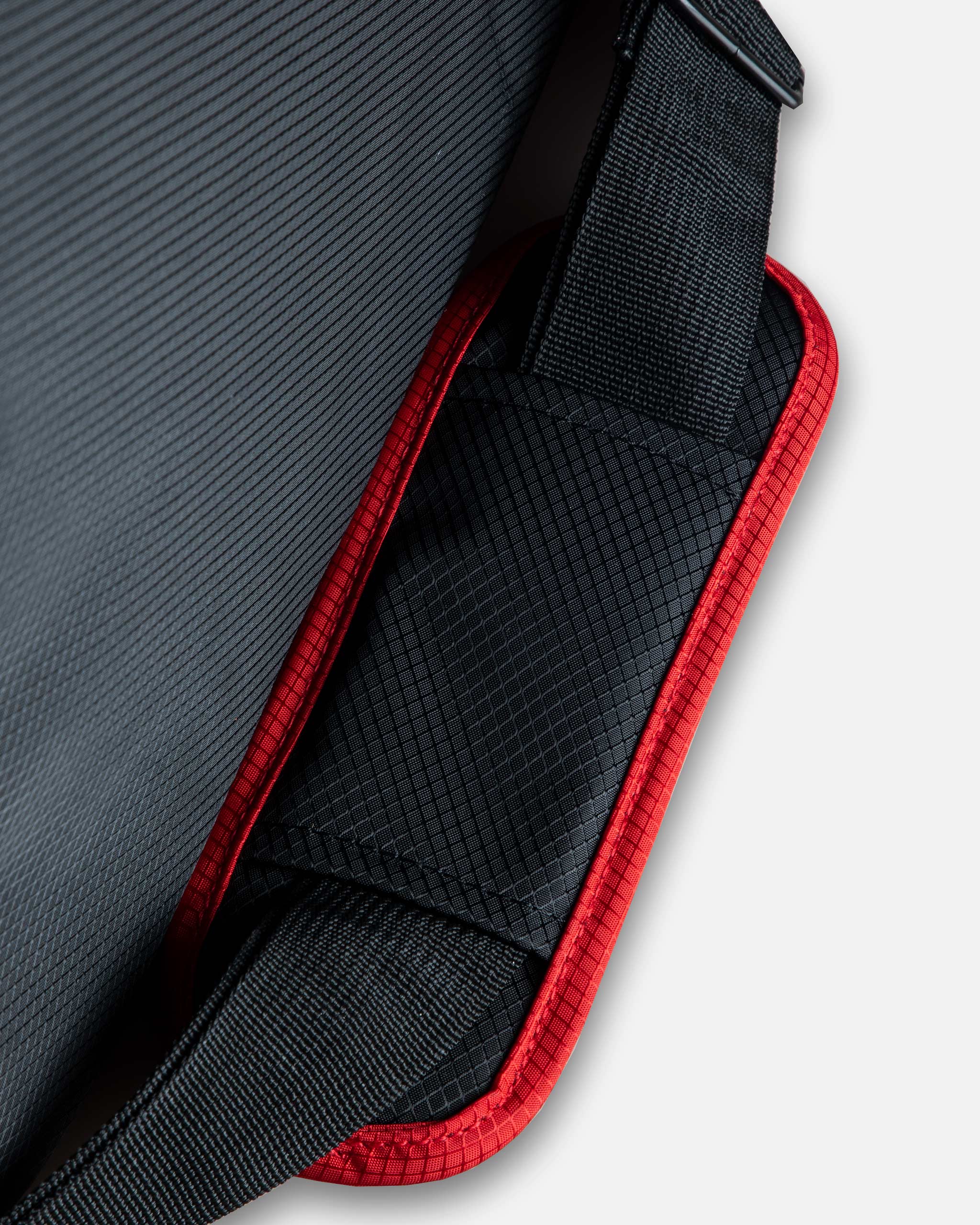 Close-up view of Adam's Random Mystery Trunk Organizer V2 showing textured black fabric with red trims and a durable strap.
