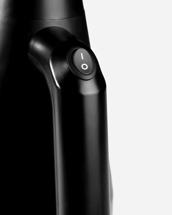 Close-up of a black handheld mini air cannon with a power button illuminating the letter "I" symbol, sleek black finish, highlighting the device's modern design.