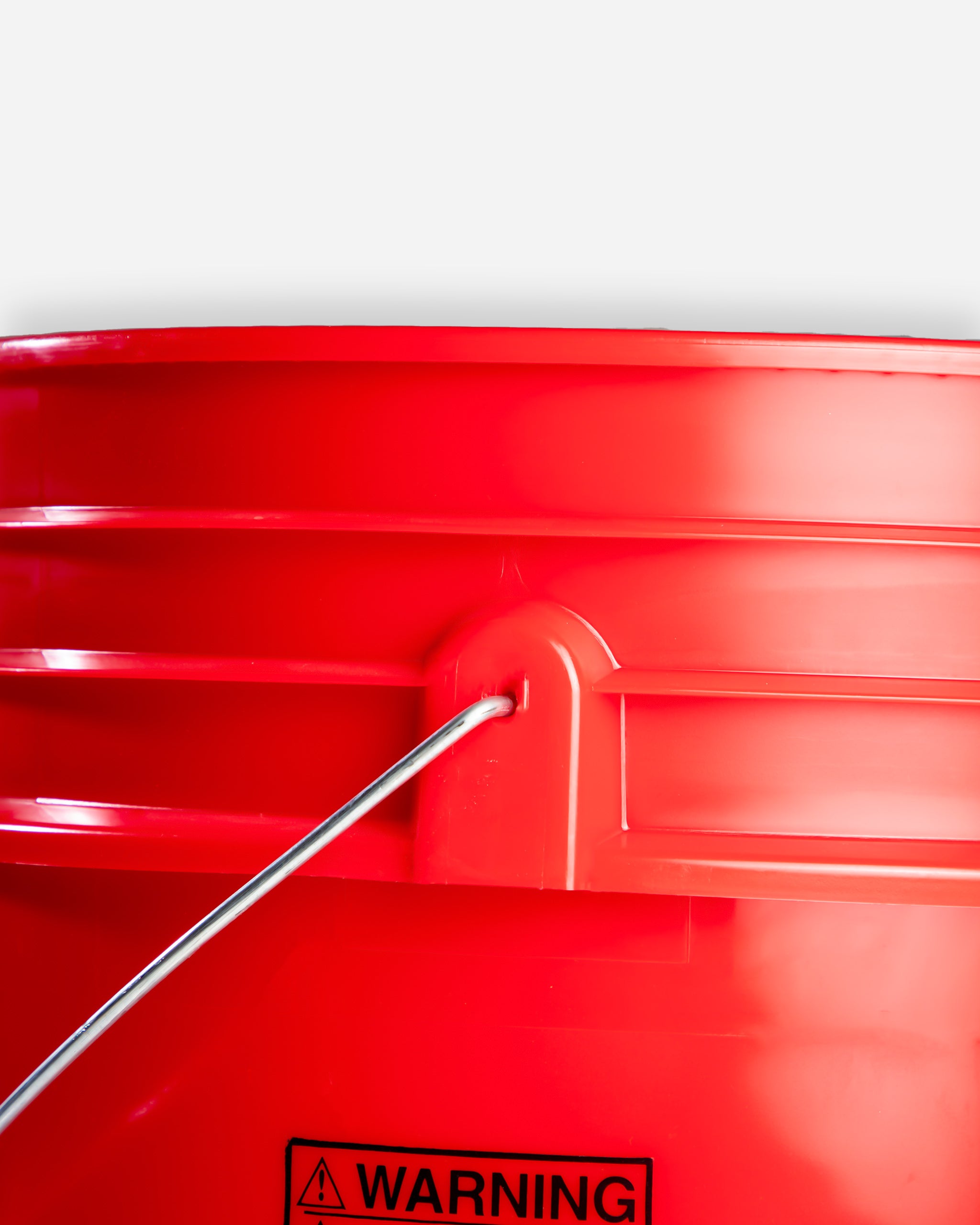 Close-up view of a bright red Adam's Mystery Bucket priced at $69.99, featuring a silver handle and visible warning label on its side.