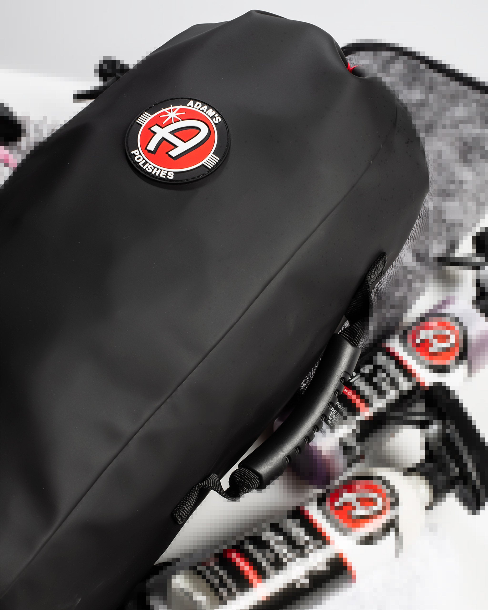 Alt text: Close-up of a black drawstring bag priced at $49.99 featuring the Adam's Polishes logo in red and white, with blurred mystery items in the background indicating the contents are undisclosed.