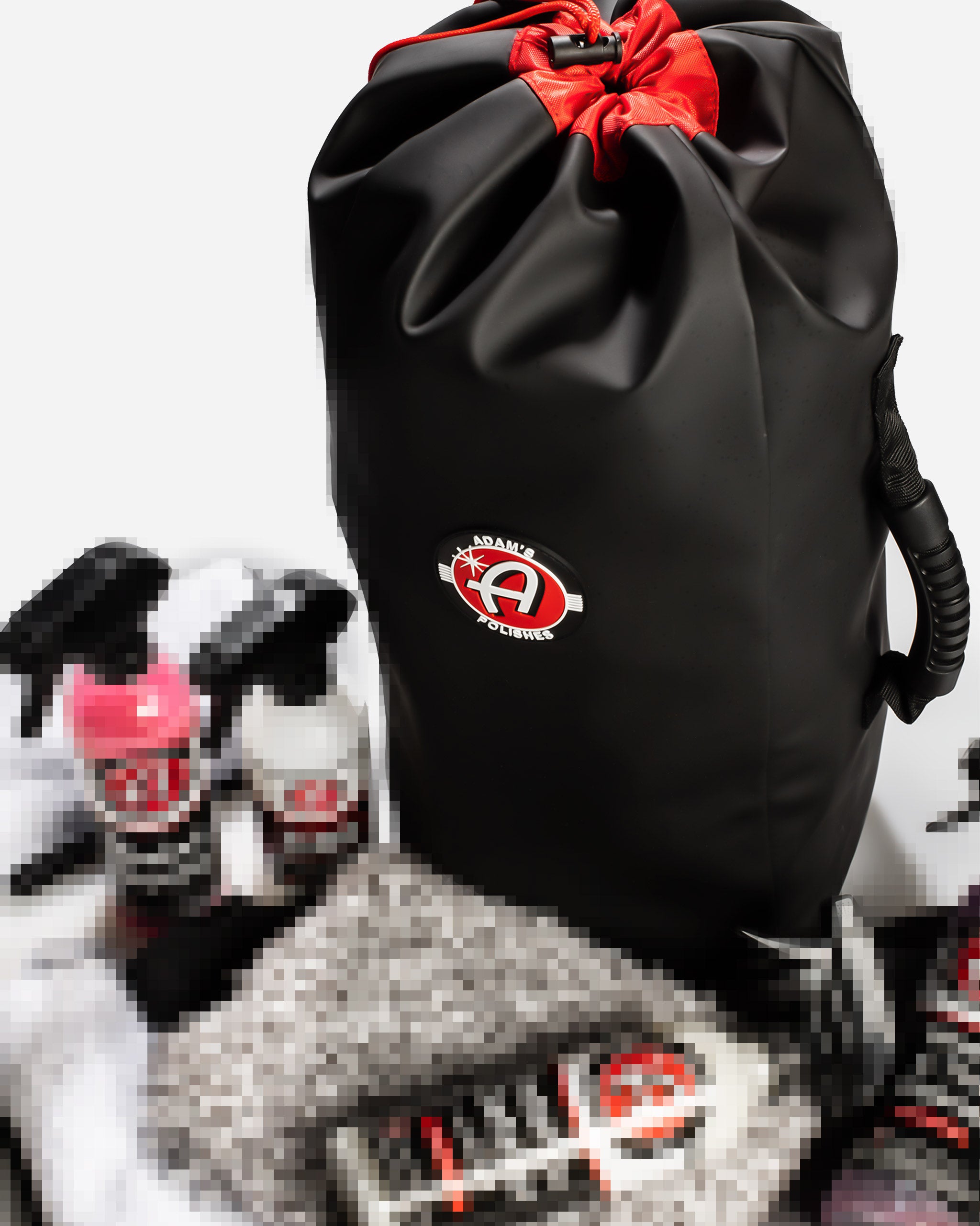 Alt text: "Adam's $49.99 Mystery Drawstring Bag featuring a sleek black design with a prominent Adam's Polishes logo, securely fastened with a vibrant red ribbon, partially revealing assorted car care products."