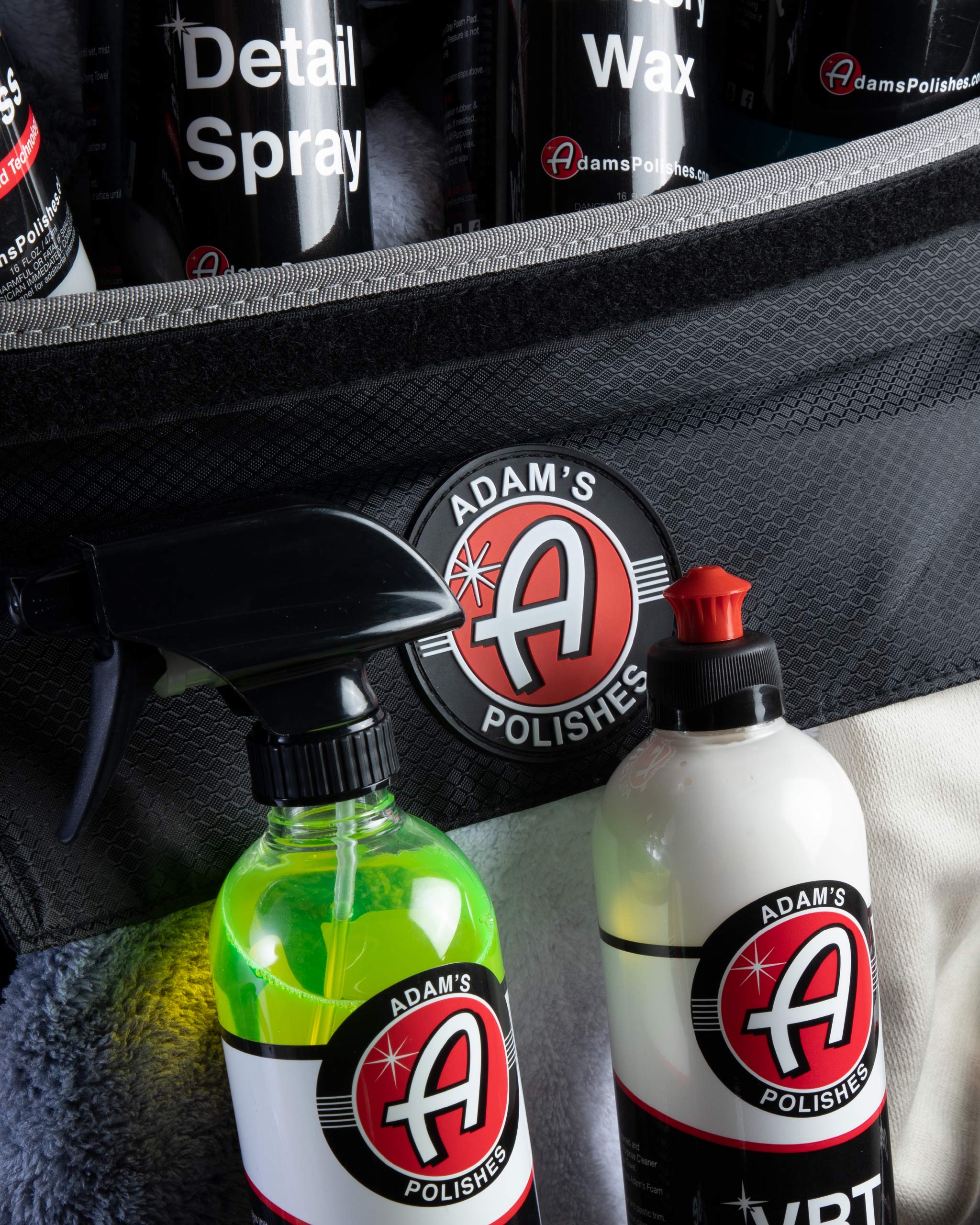 Alt text: Close-up of Adam's limited edition $99.99 Mystery Trunk Organizer, featuring car care products including Detail Spray, Wax, and VRT in a textured black trunk organizer, prominently displaying the Adam's Polishes logo.