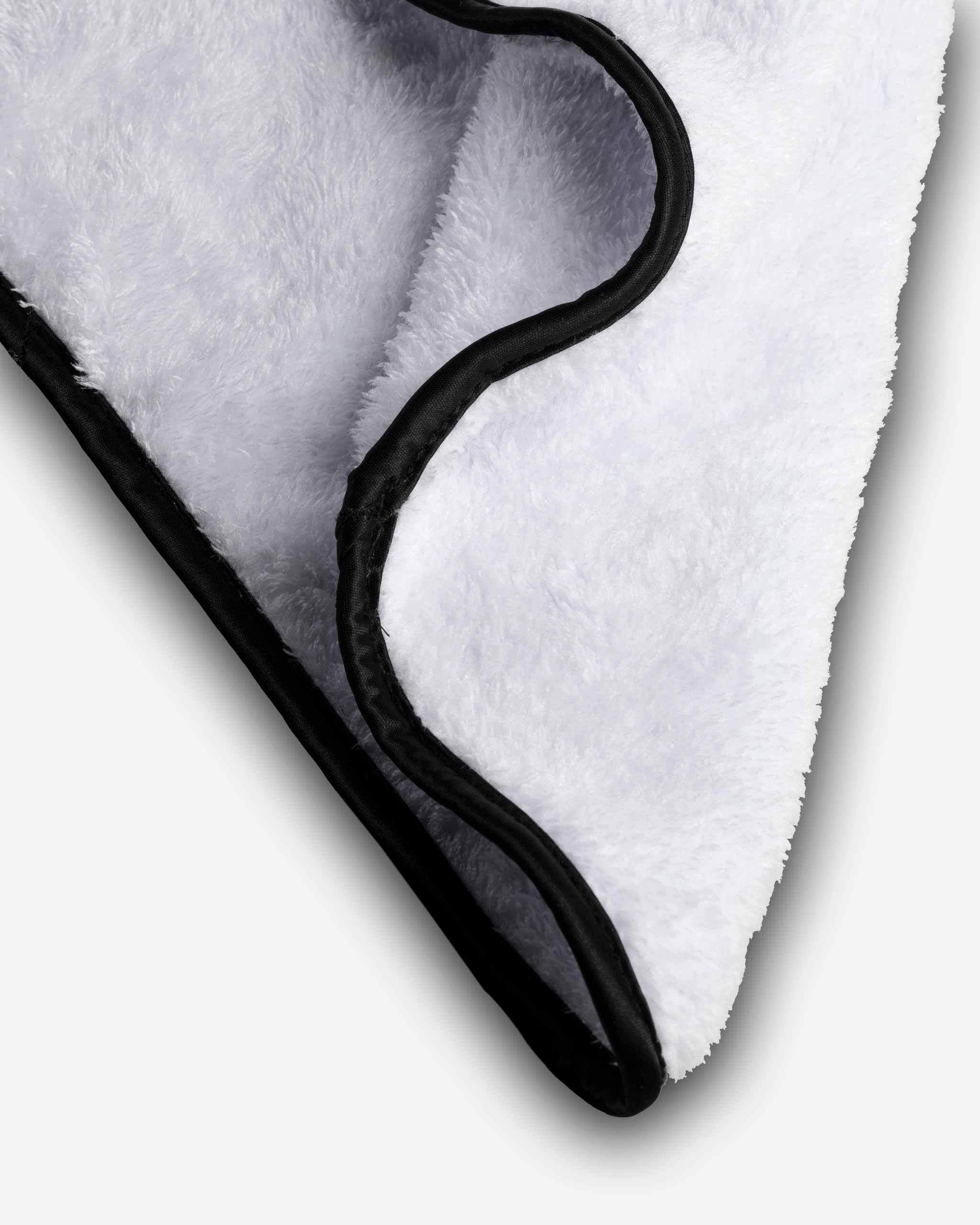 Close-up image of a white fleece blanket with a black trim.